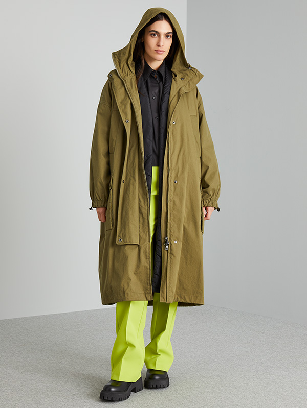 Modella indossa pantaloni di colore verde acido con parka di colore verde kaki.